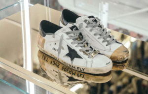 The sneakers in the image are Golden Goose sneakers, a distressed style sneaker made by the Italian fashion brand Golden Goose Golden Goose is known for its high-fashion sneakers with a vintage, distressed look. The brand is popular among celebrities and fashion influencers.