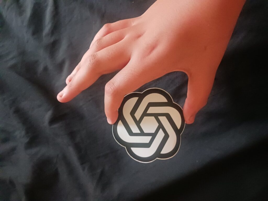 A person holding a phone showing the OpenAI icon