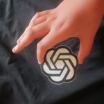 A person holding a phone showing the OpenAI icon