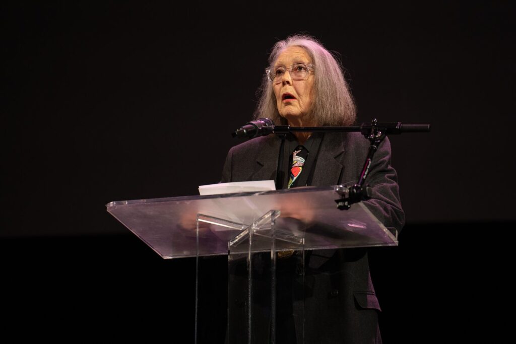 Anne Carson reading at a podium